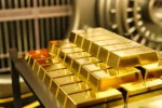 Barrinhas de ouro empilhadas em prateleira dentro de um cofre de banco, simbolizando reservas monetárias nacionais e segurança econômica.