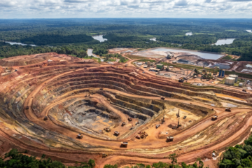 Vista aérea de mina de ouro a céu aberto no Brasil com maquinário industrial e terraços escavados em grande escala